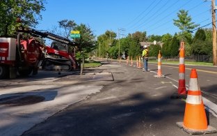 orange traffic cones, construction worker, and excavation machines on residential road