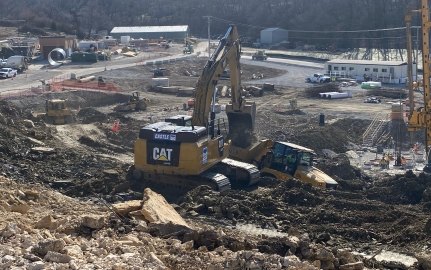 Active construction site with yellow excavator, bulldozer, pile boring machine